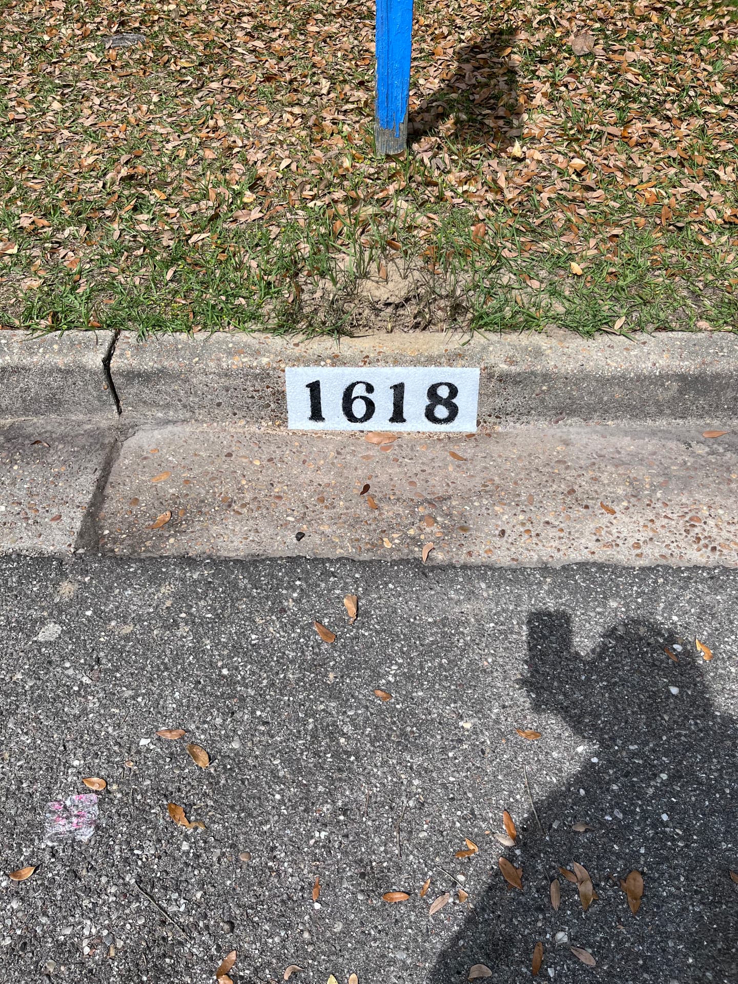 Curb address 1618 painted in high-contrast black on a white block